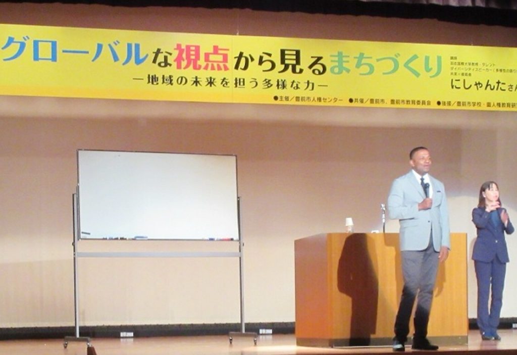 にしゃんたが、人権週間の特別講演で観客に語りかける姿。国際理解とダイバーシティをテーマにした講演が反響を呼んでいます。