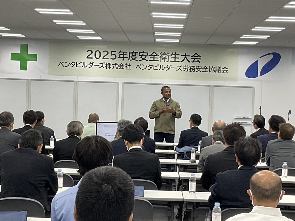 ユーモアを交えつつ、安全と多文化共生の大切さを伝え、会場が笑いに包まれている安全大会講演中のにしゃんたの写真。