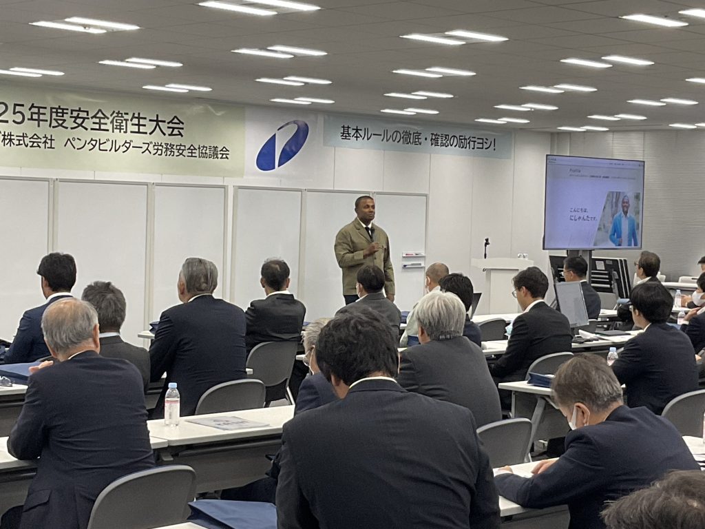 安全大会で基調講演を行うにしゃんたの写真。建設現場の安全と外国人スタッフとのコミュニケーションをテーマに登壇している様子。